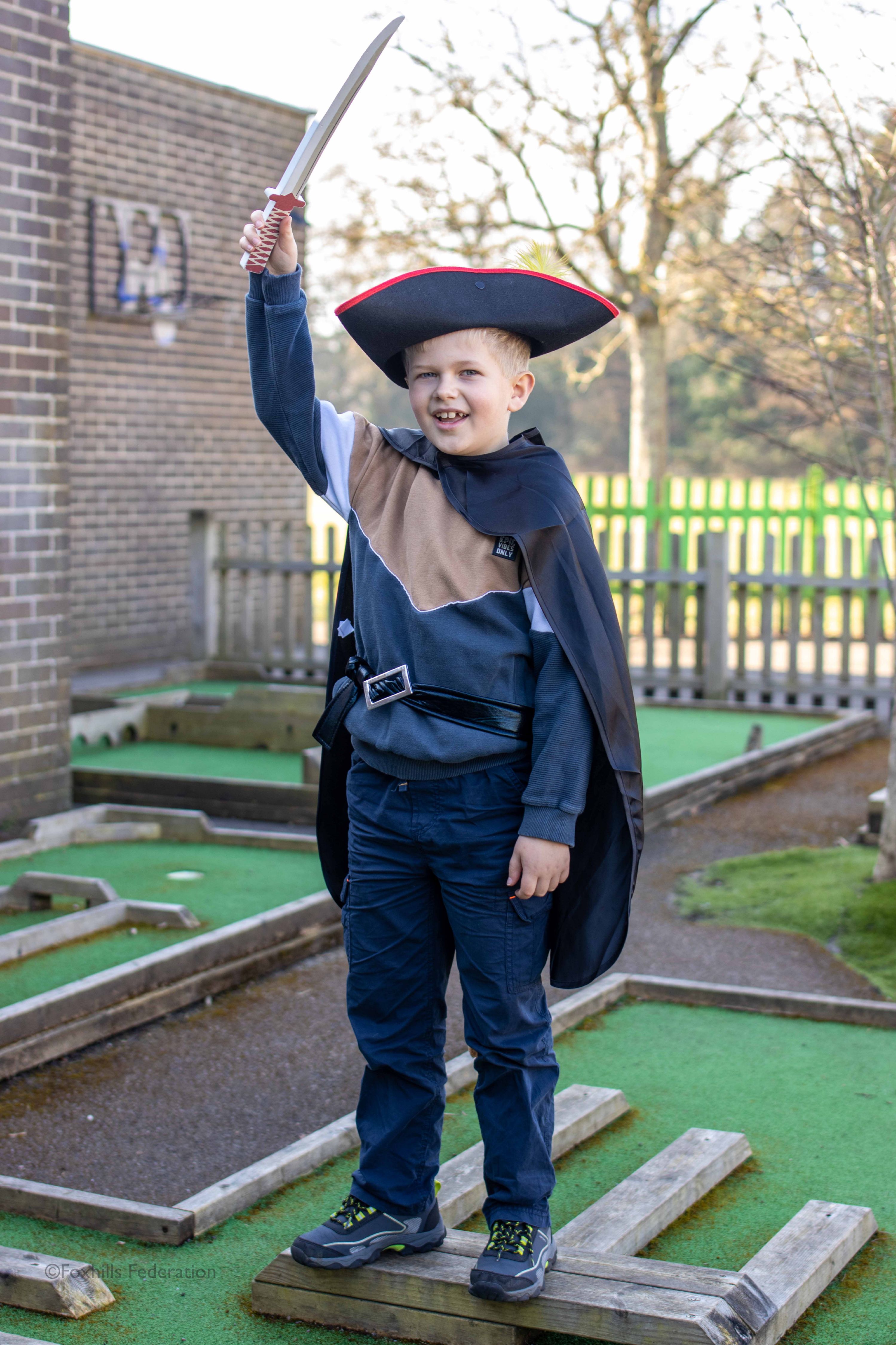 A child is dressed as a pirate and holds a sword