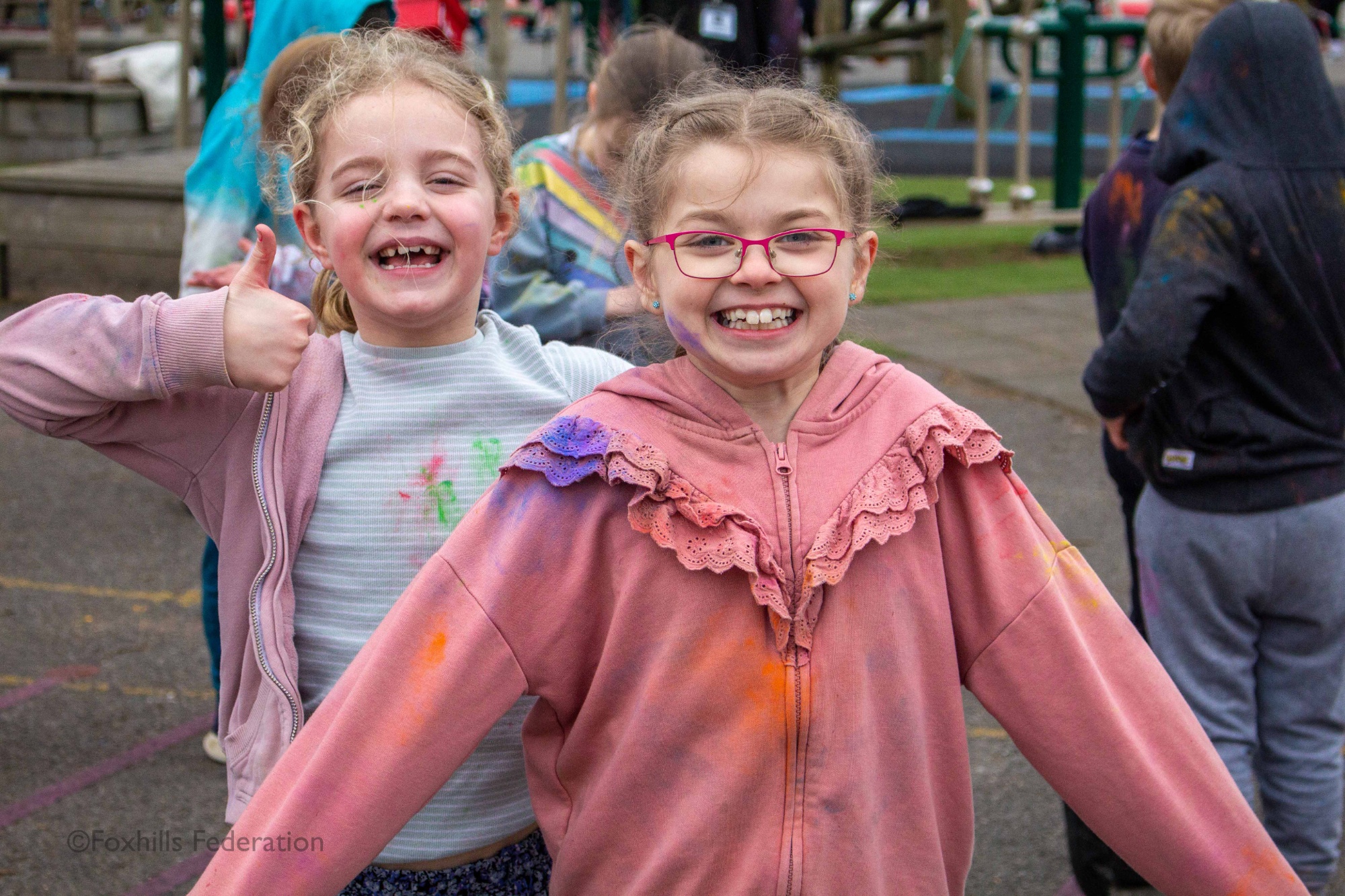 Two girls smile at the camera while covered in paint