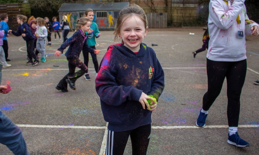 A Year 3 girl, covered in powder paint smiles at the camera.